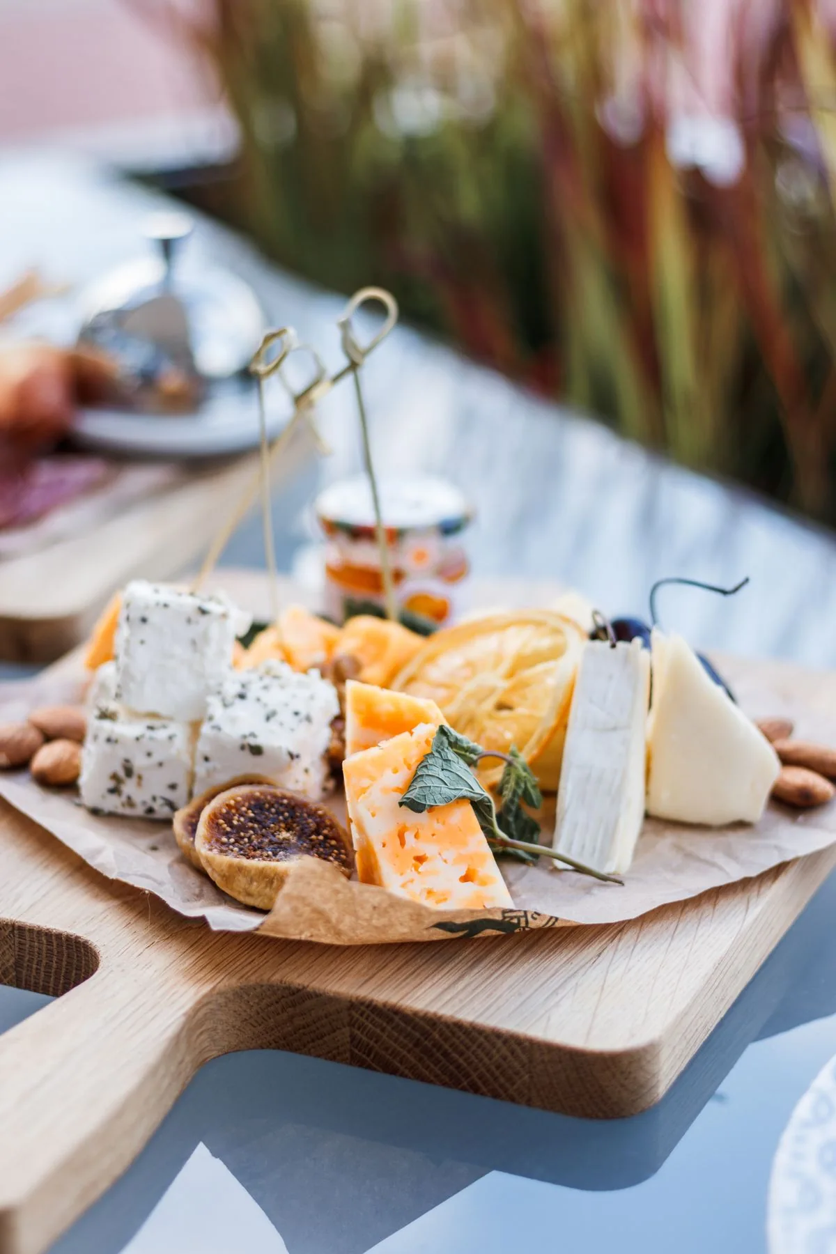 Real mixed cheese board with fig, almonds, citrus and fresh herbs